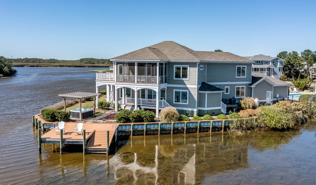 A charming house on the water with a dock, representing a summer getaway in Virginia Beach.