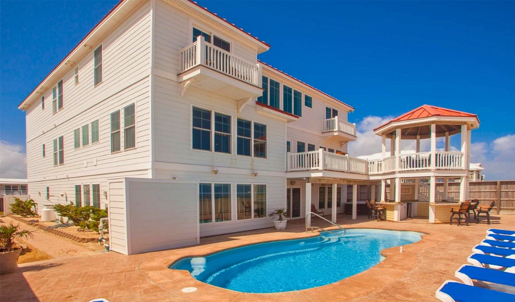 A large white house with a pool and sun deck, showcasing Oceanic Serenade by Little Neck Virginia Beach Home Builders.