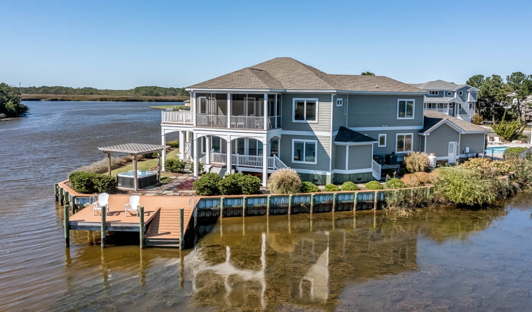 A waterfront house with a dock, showcasing the Summer Baycation by Strawbridge Virginia Beach Homebuilders.