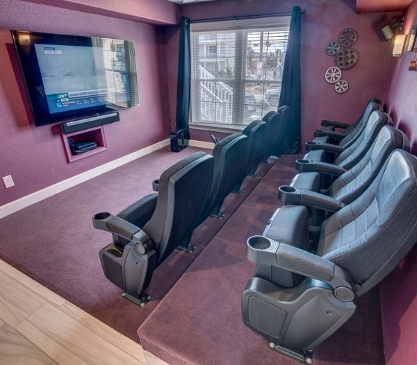 A cozy home theater featuring a couch and chairs, designed for functional living space in a garage conversion.