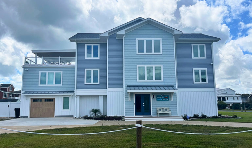 Exterior view of a blue house with white trim and blue siding, part of a garage conversion project in Virginia Beach.