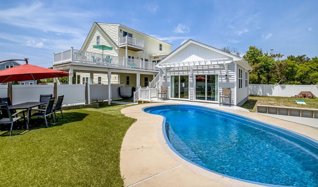 A remodeled house featuring a pool and patio area, showcasing the work of Bikini Blonde, a Virginia Beach contractor.