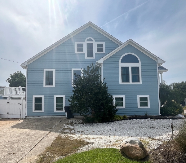A blue house featuring white trim and a driveway, representing value-boosting renovations by a Virginia Beach contractor.