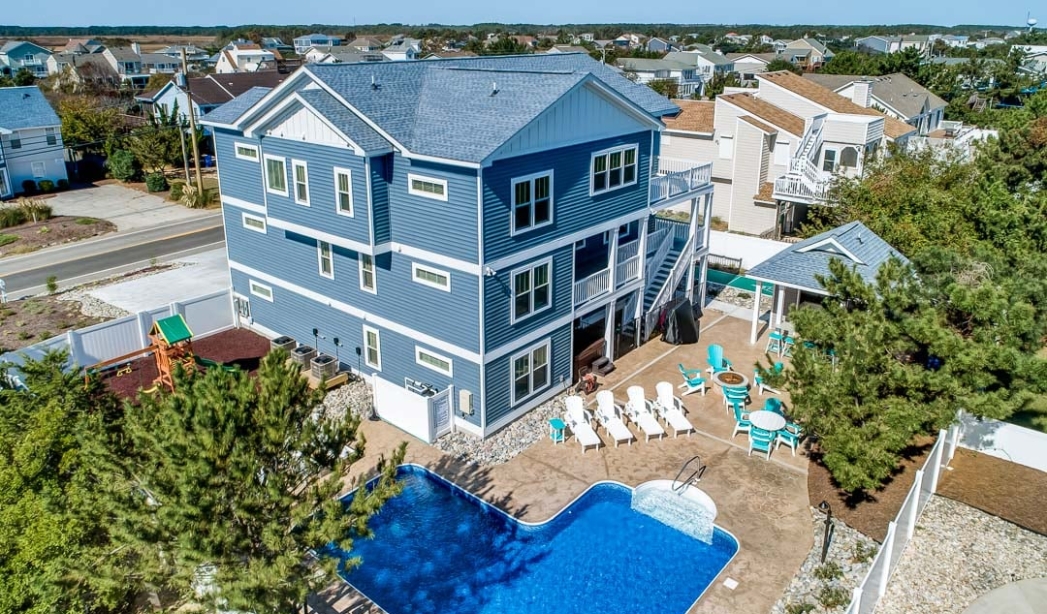 Exterior view of a blue house featuring a pool and deck, designed by All-Sea-Sun, a Virginia Beach contractor.