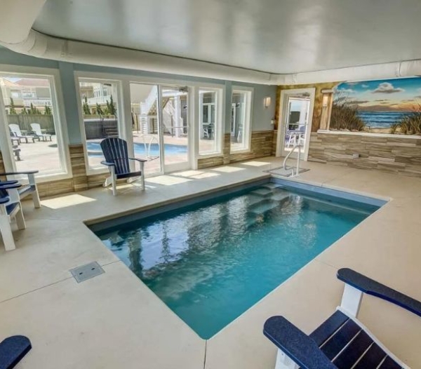 Elegant home pool with blue seating and a colorful mural, representing bespoke design work by a Virginia Beach contractor.
