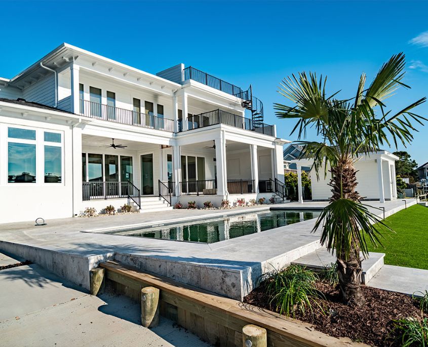 A spacious custom coastal residence featuring large covered outdoor living areas, modern railings, and a private pool, showcasing RBC Homes’ expertise in high-end design, durable construction, and seamless indoor-outdoor living.
