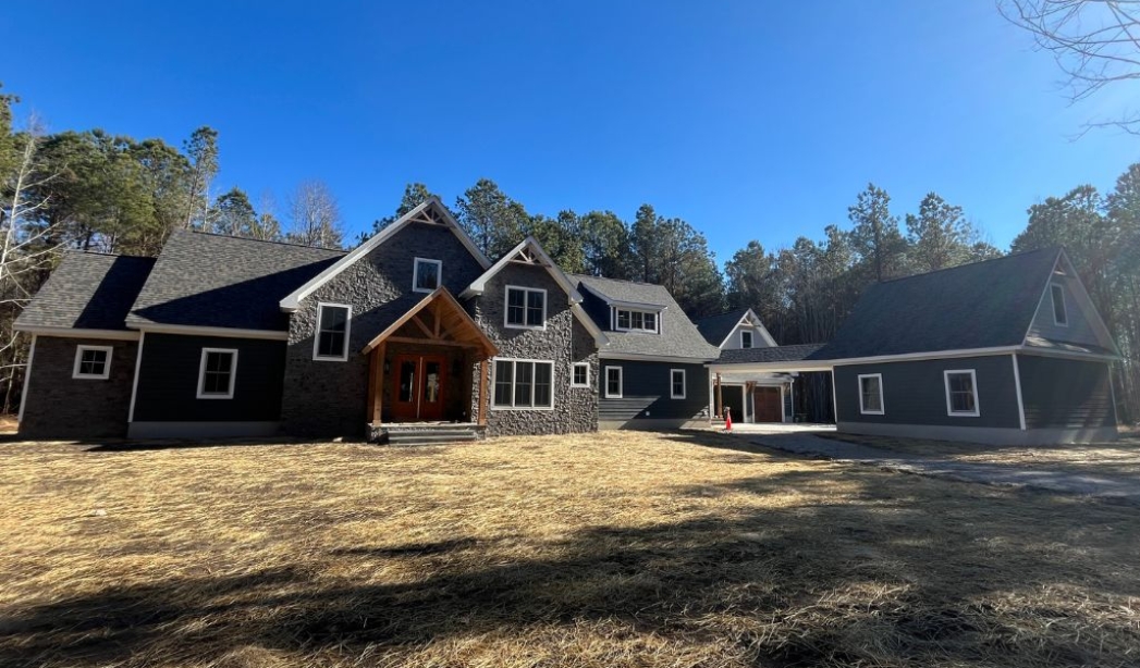 A beautifully built custom residence featuring a stone exterior, multiple gables, and an expansive backyard setting, highlighting RBC Homes’ expertise in durable construction.
