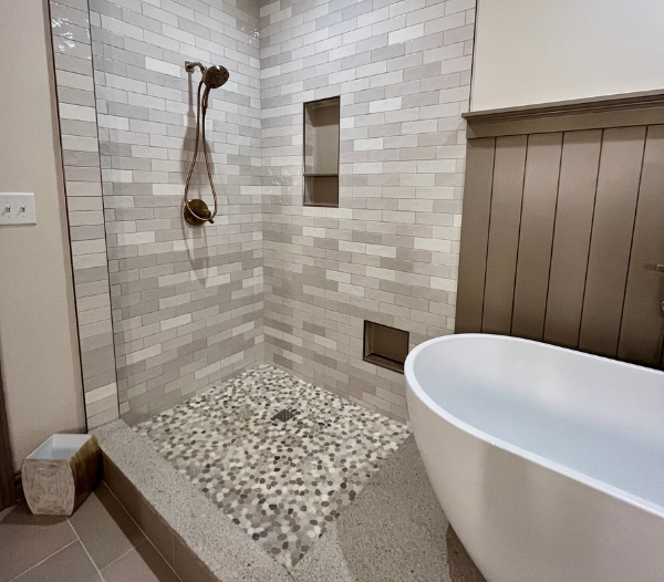 A personalized bathroom renovation featuring a raised walk-in shower with textured pebble flooring, reflecting RBC Homes’ custom craftsmanship and tailored design solutions for modern comfort.