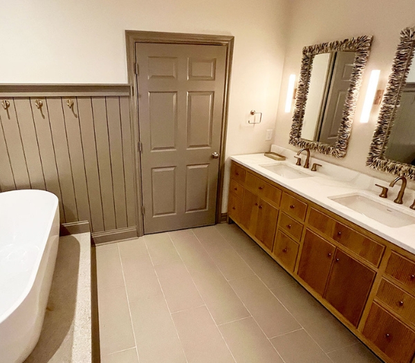 A newly remodeled bathroom featuring a sleek soaking tub, dual sinks with spacious countertops, framed mirrors, and elegant wood finishes, highlighting RBC Homes’ focus on comfort, functionality, and refined interior design.