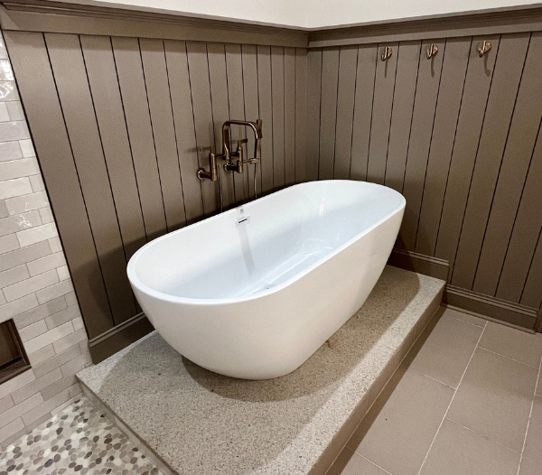 A stylish bathroom renovation featuring a sleek freestanding bathtub, elevated stone platform, and contemporary wall finishes, and increased home value through RBC Homes’ quality craftsmanship.