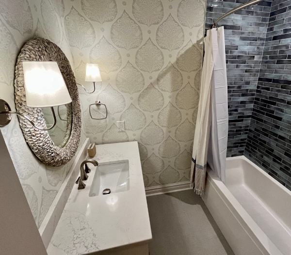 A refined bathroom renovation showcasing a sleek marble countertop vanity, decorative wall finishes, and a durable tiled shower and tub area, highlighting RBC Homes’ commitment to quality materials.