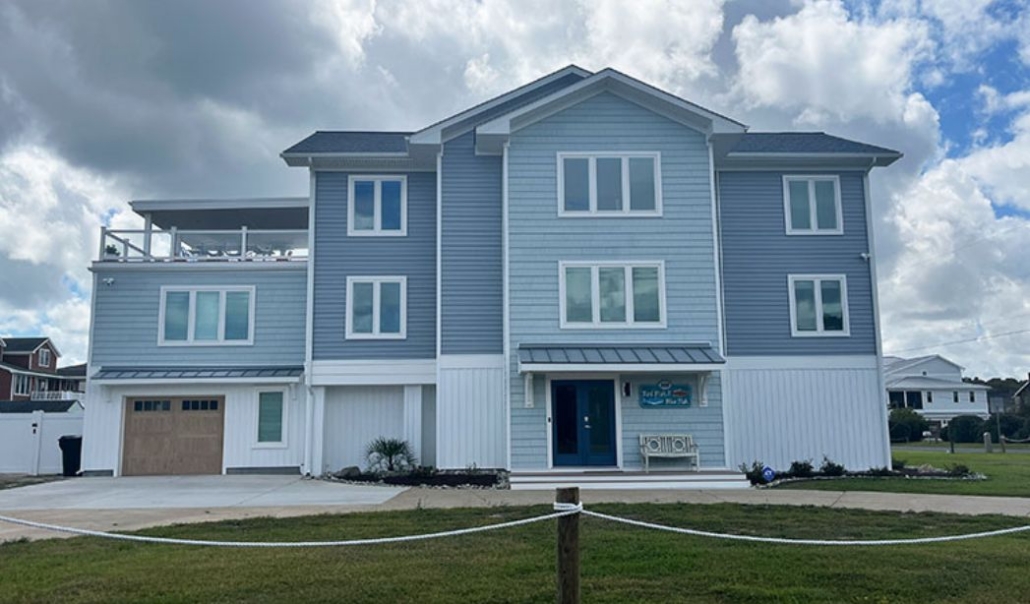 Beach house exterior featuring blue vinyl siding with white trim and attached garage.