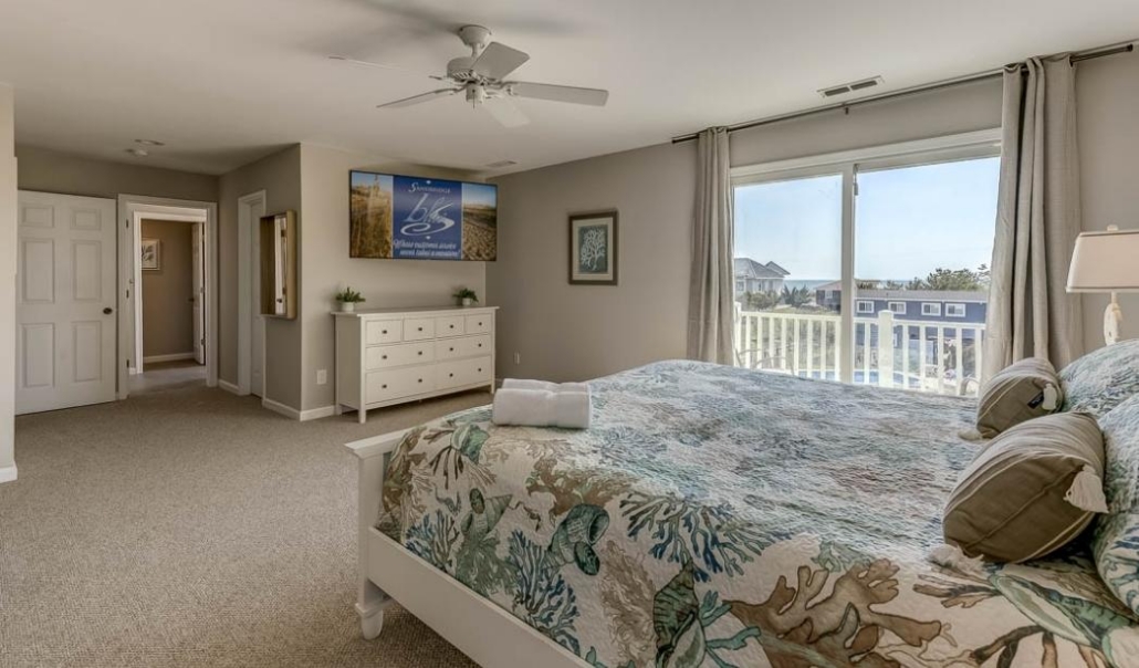 Elegant master bedroom suite showcasing a spacious bed and a flat screen TV, highlighting luxury design features.