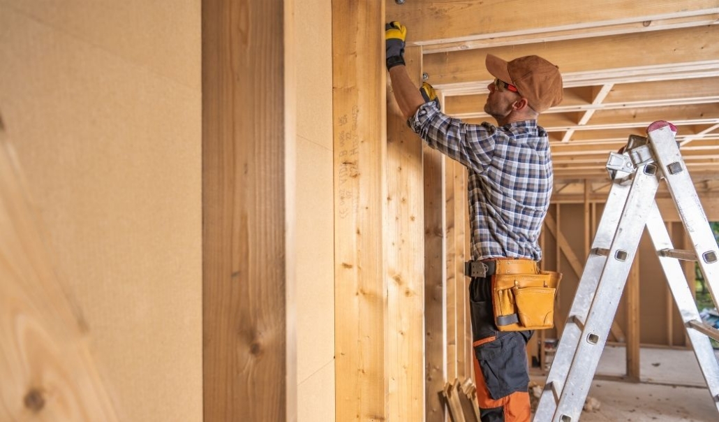 A man is constructing a wall with wood framing as part of a master bedroom suite addition.