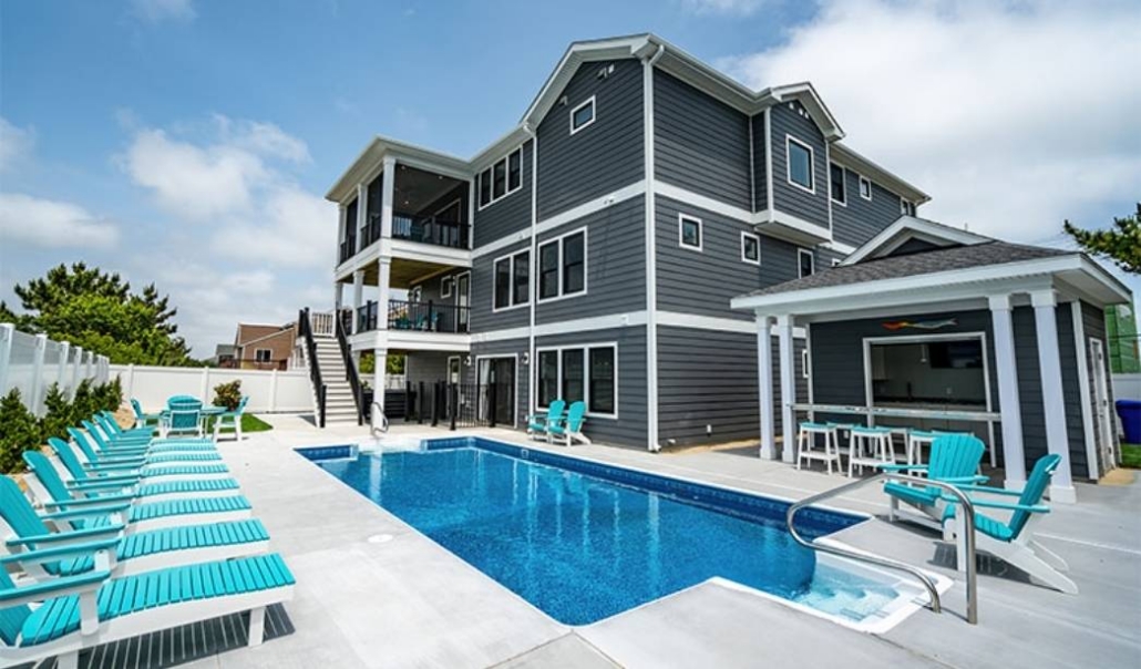 Modern custom coastal home featuring outdoor amenities, poolside seating, and open living design.
