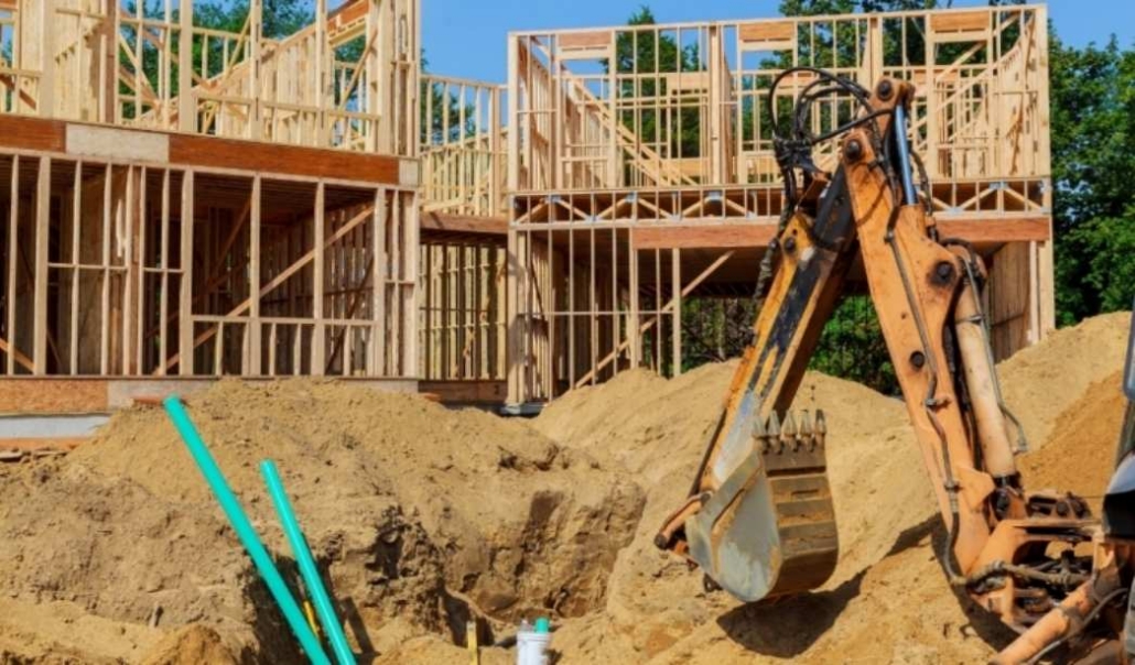 Residential custom home under construction showing structural framing and site development.