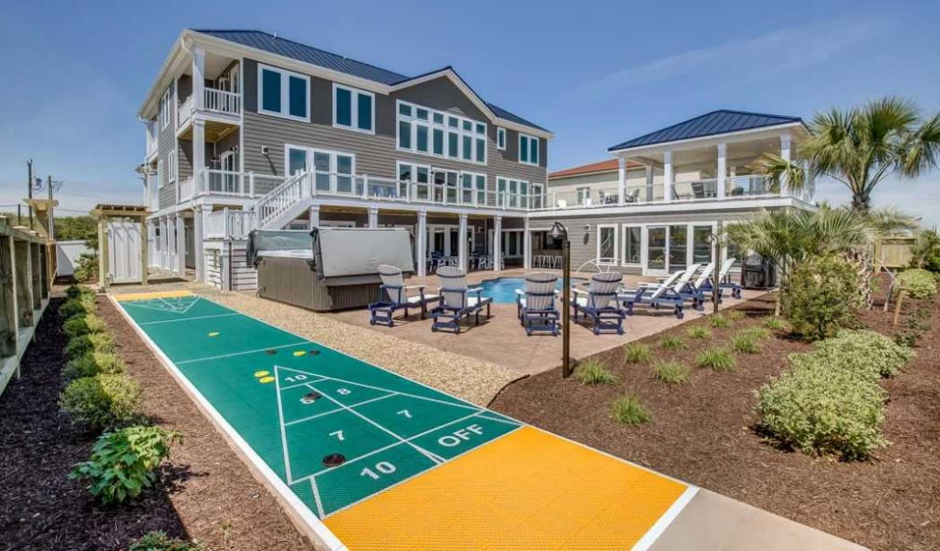 Coastal home with a spacious yard, private pool, outdoor seating, and a backyard shuffleboard court.