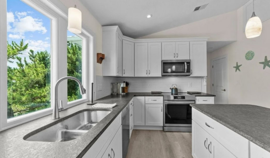Kitchen addition with white cabinets, gray countertops, stainless steel appliances, and large windows.